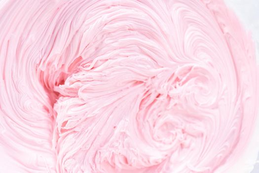 Close up view. Mixing in pink food coloring into a vanilla buttercream frosting for decorating funfettti bundt cake.