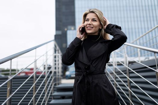 portrait of a confident middle-aged business woman talking on a mobile phone against the backdrop of an office skyscraper.
