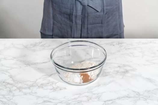 Mixing dry ingredients in a large glass mixing bowl to bake soft oatmeal raisin walnut cookies.