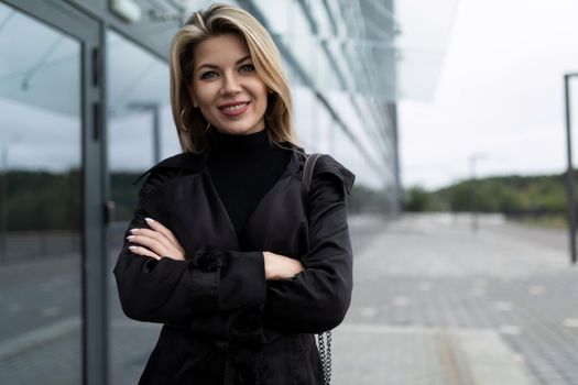 portrait of a successful business woman in a black business suit next to the entrance to the office building.