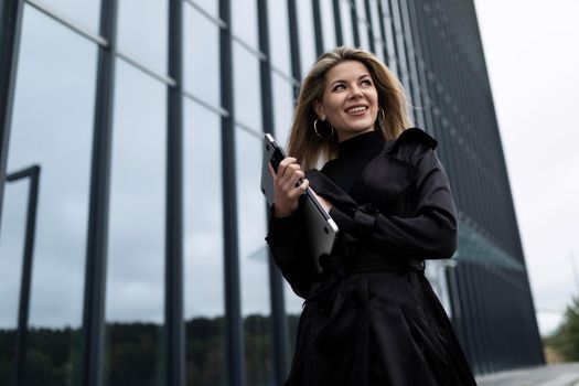 portrait of a successful business woman with a laptop in her hands against the backdrop of an office skyscraper.