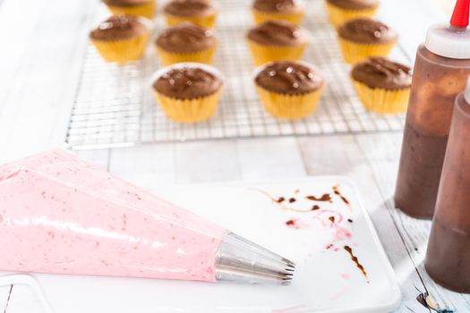 Raspberry cream cheese frosting in a piping bag with metal tip.