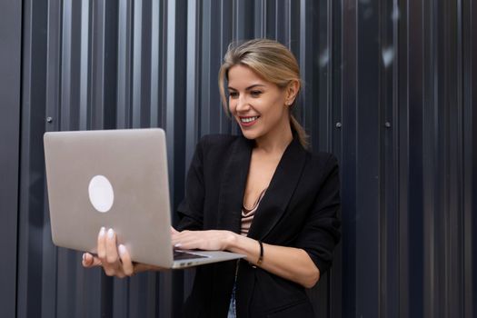 middle-aged woman office worker with a laptop in her hands against a gray wall.