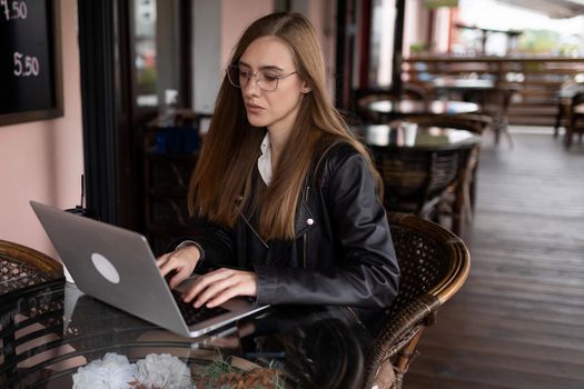 young woman working on a laptop in a city cafe.