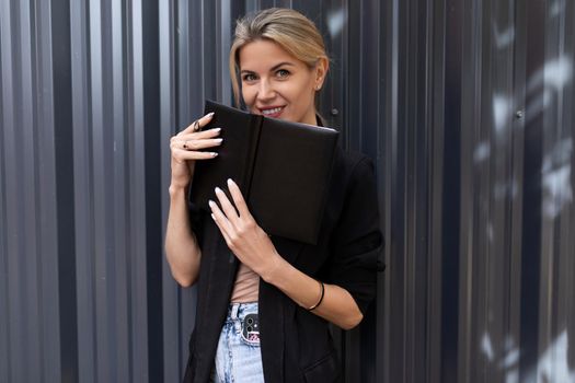 portrait of a mischievous stylish female office worker on the background of a gray wall in the office.