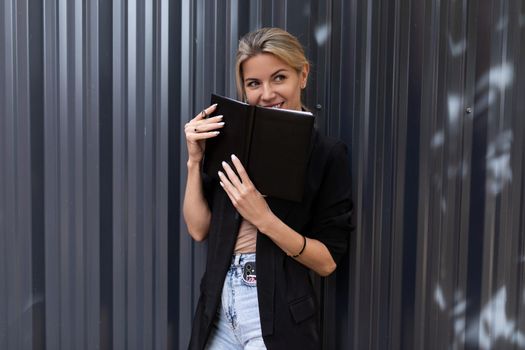 office worker middle-aged woman with a smile holding a notebook in her hands looking at the camera.