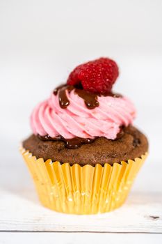Gourmet chocolate raspberry cupcakes drizzled with chocolate ganache and topped with a fresh raspberry.