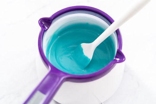 Melting chocolate melts in a candy melting pot to prepare mermaid cakesicles.