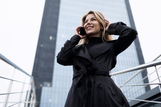 confident businesswoman speaks on a mobile phone against the backdrop of a glass office.