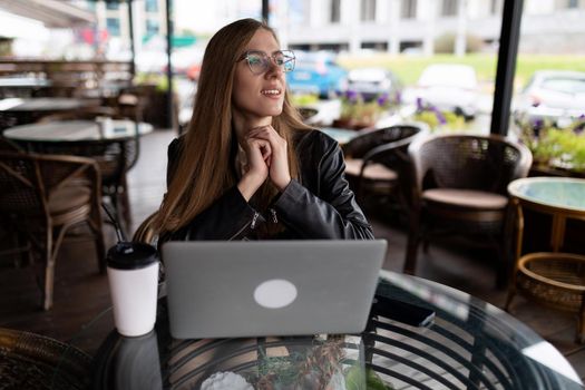 young female freelancer working on a laptop in a city cafe.