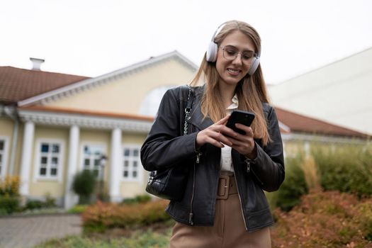 young woman goes to work listening to music in headphones via mobile phone.