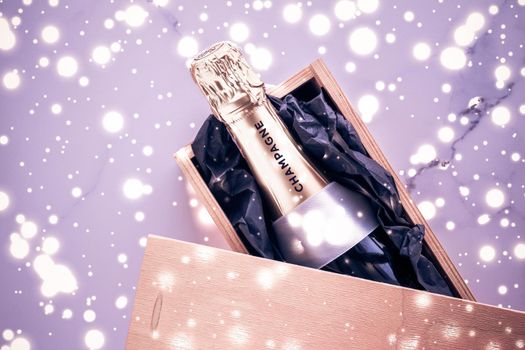 Celebration, drink and branding concept - Champagne bottle and gift box on purple holiday glitter, New Years, Christmas, Valentines Day, winter present and luxury product packaging for beverage brand