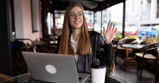 young woman student working online in a cafe on a laptop with a cup of coffee.