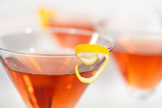 Cosmopolitan cocktail in a martini glass and decorated with a lemon swirl.