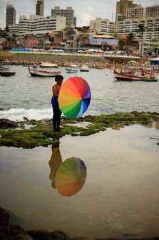 salvador, bahia / brazil - february 2, 2016: umbrella reflection is seen in a puddle of sea water on Rio Vermelho beach in the city of Salvador.
