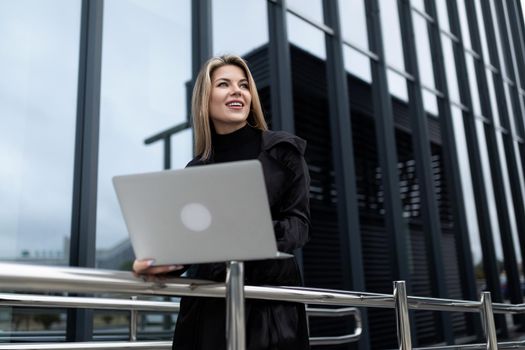woman businessman head working on a laptop online against the backdrop of an office building.