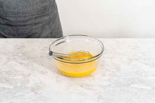 Mixing ingredients with a hand whisk in a glass mixing bowl to make egg bites.