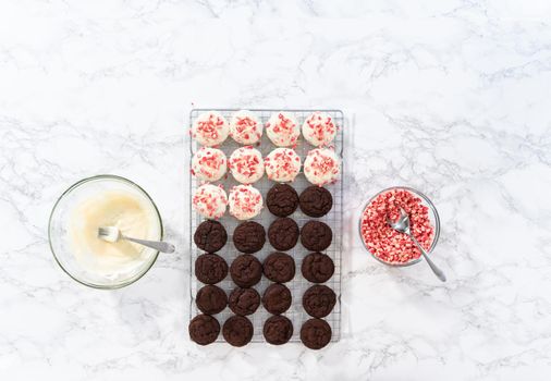 Flat lay. Dipping chocolate cookies into the melted white chocolate to prepare peppermint white chocolate cookies.