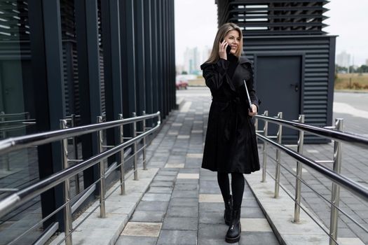 a middle-aged business woman walks into an office building talking on the phone.