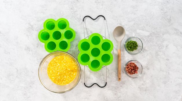 Flat lay. Filling silicone molds with egg mixture to make egg bites in a pressure cooker.
