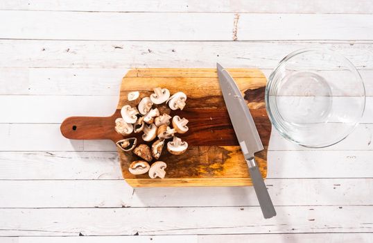 Flat lay. Cutting organic bella mushrooms on a wood cutting board.