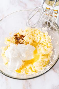 Mixing ingredients in a large glass mixing bowl to bake apple bundt cake with caramel glaze.