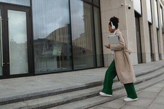 young american woman with laptop and headphones enters the business center.