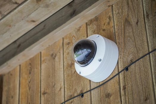 Image of Round shaped weathersealed Security camera on the wooden wall