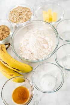 Measured ingredients in glass mixing bowls to bake banana oatmeal muffins.