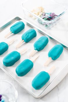Decorating cakesicles with drizzled chocolate, chocolate mermaid tails, and seashells.