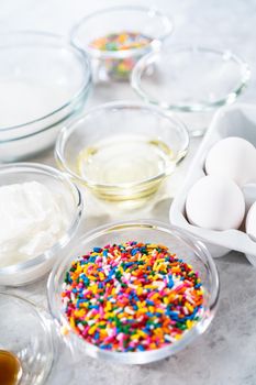 Ingredients in glass mixing bowls to bake funfettti bundt cake.