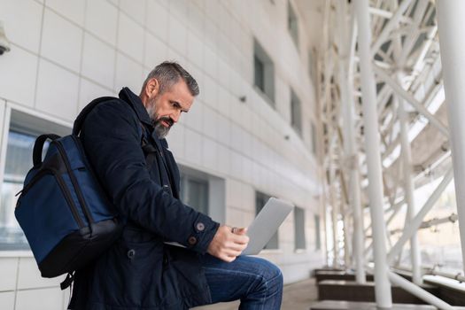 businessman at the airport waiting to board the plane working online on a laptop.