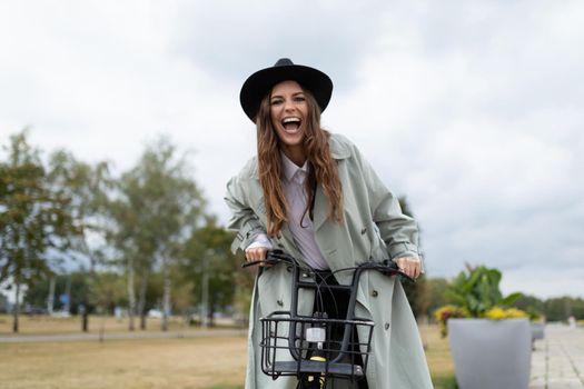 young woman laughing while sitting on a bicycle looking at the camera in a city park.