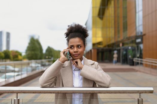 african american woman businessman concentratedly talking on a mobile phone on the background of an office building.