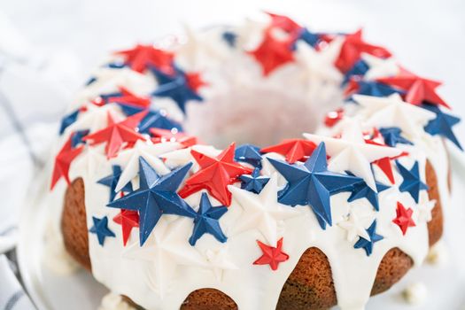 July 4th bundt cake covered with a vanilla glaze and decorated with chocolate stars on a white plate.