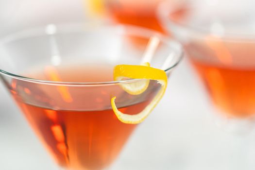 Cosmopolitan cocktail in a martini glass and decorated with a lemon swirl.