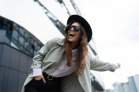 young stylish woman catches a taxi with her hand outstretched against the backdrop of an office building.