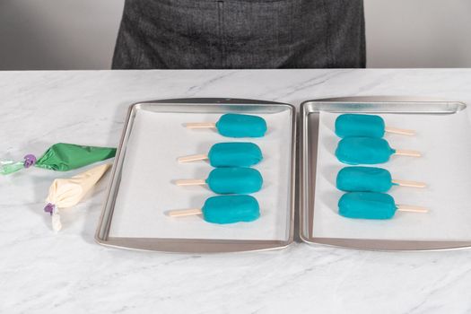 Decorating cakesicles with drizzled chocolate, chocolate mermaid tails, and seashells.