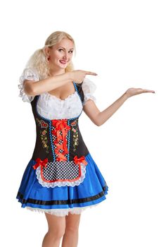 Beautiful young blond girl in dirndl drinks out of oktoberfest beer stein. Isolated on white background. pointing finger and smiling. copyspace desing concept