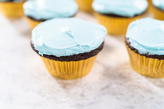 Decorating chocolate cupcakes with buttercream frosting and rainbow candy.
