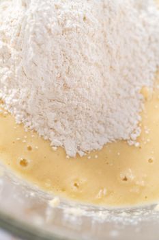 Mixing ingredients in a large glass mixing bowl to bake apple bundt cake with caramel glaze.