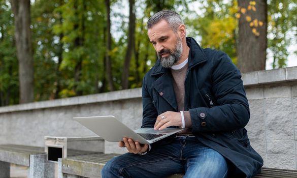 businessman working online on laptop in city park.