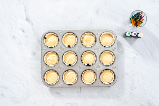 Flat lay. Vanilla cupcake batter in foil cupcake liners to bake Mardi Gras vanilla cupcakes.