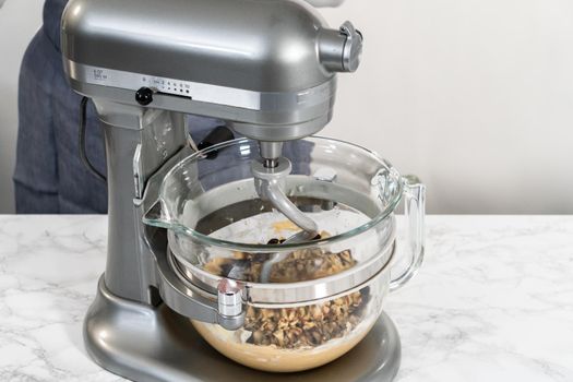 Mixing ingredients in a kitchen stand mixer to bake soft oatmeal raisin walnut cookies.