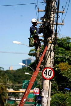 salvador, bahia / brazil - July 15, 2016: The man is seen working on the fixed telephone network next to the pole in the city of Salvador.

