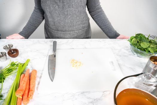 Cutting organic garlic on a white cutting board.