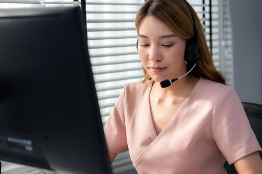 Competent female operator working on computer and while talking with clients. Concept relevant to both call centers and customer service offices.