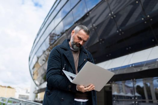 male entrepreneur working online on a laptop before boarding a plane at the airport.