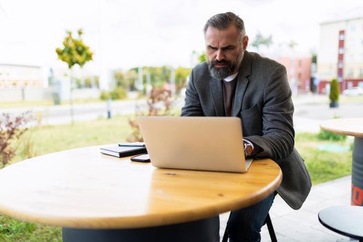 mature male entrepreneur working online in cafe on laptop.