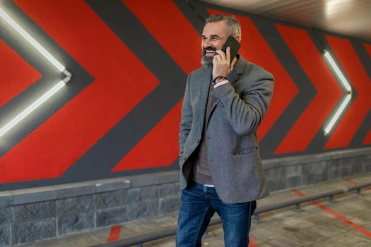 portrait of a serious ambitious successful mature male businessman with a mobile phone against the background of red arrows.